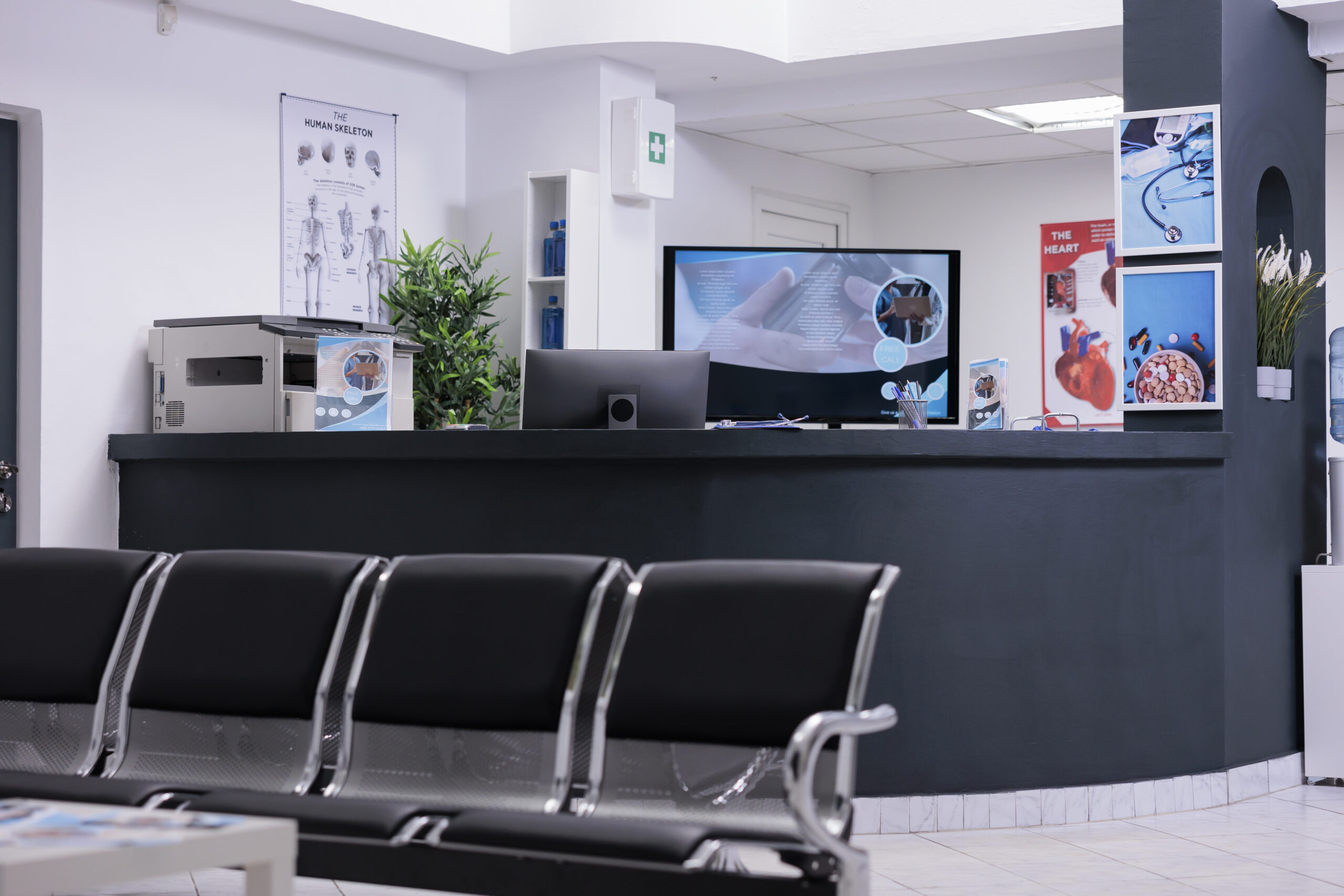 Clinic registration counter in waiting room lobby, computer to make checkup appointments with healthcare report papers. Empty hospital reception desk with medical forms and insurance support.