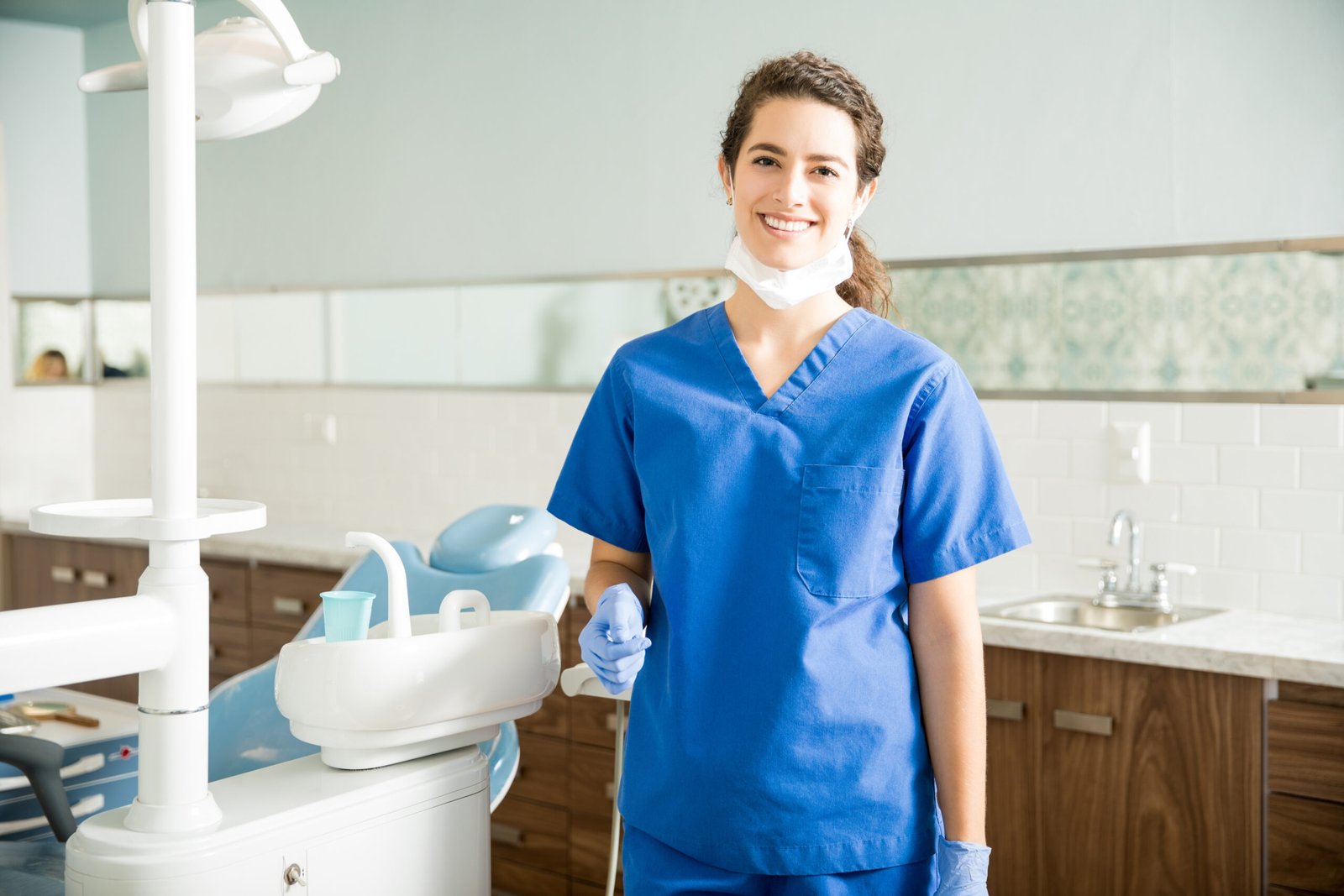 Portrait of smiling female dentist wearing scrubs while standing at clinic