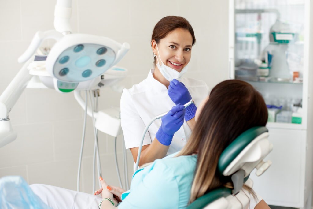 Woman dentist treats a patient. A woman in a mask sits in a dental chair in the clinic. Medicine, health, dentistry concept.